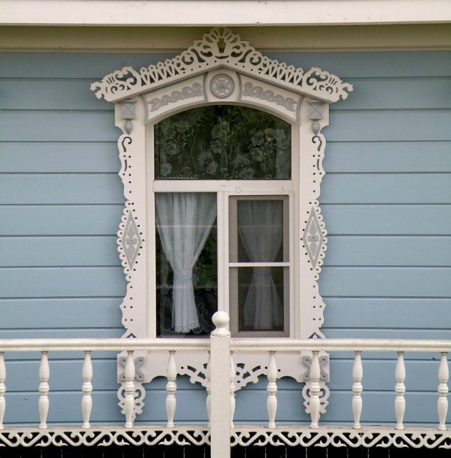 Пластиковый белый наличник на металлопластиковых окнах современного деревянного дома 