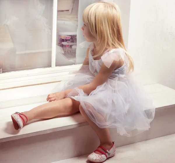 Девочка 3 лет в белом платье возле окна — стоковое фото
