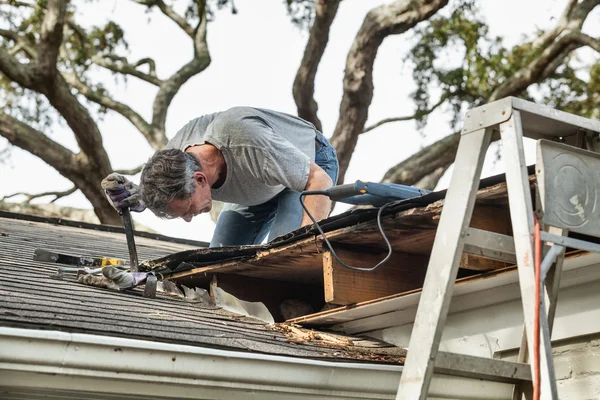Человек, проверяя и восстанавливая протекает крыша дома — стоковое фото
