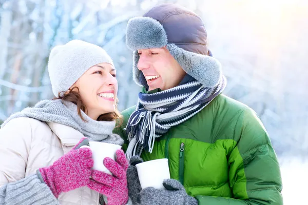 Счастливая пара с горячими напитками на открытом воздухе. Зимние каникулы — стоковое фото