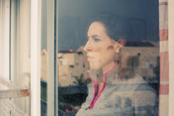 Женщина смотрит в окно — стоковое фото
