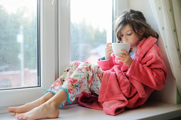 Красивая маленькая девочка в халате с чашкой чая — стоковое фото