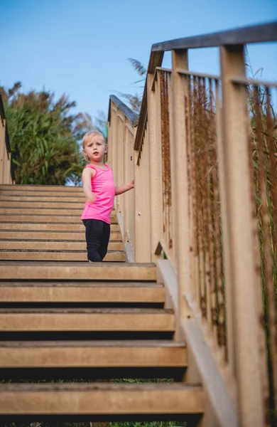 Ребенка стоя на деревянные ступени на пляже, глядя вниз — стоковое фото