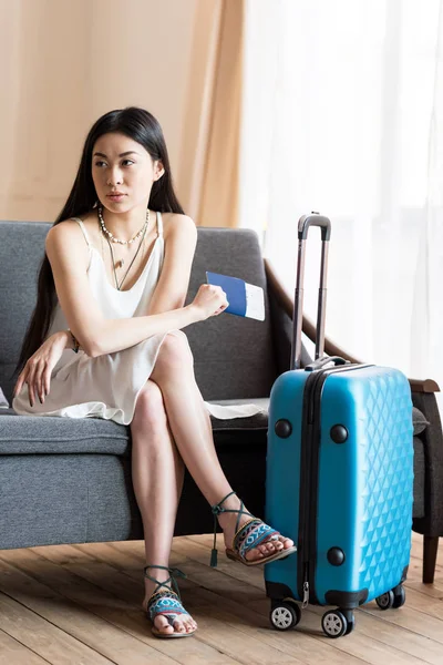 Азиатская женщина-путешественница сидит с чемоданом — стоковое фото