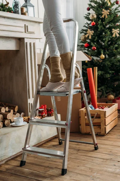 Женщина, украшая комнату на Рождество на стремянка — стоковое фото
