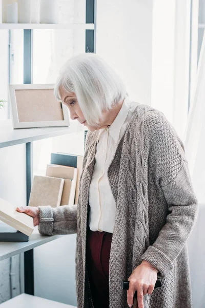 Side View Senior Woman Walking Stick Choosing Book Read Home — стоковое фото