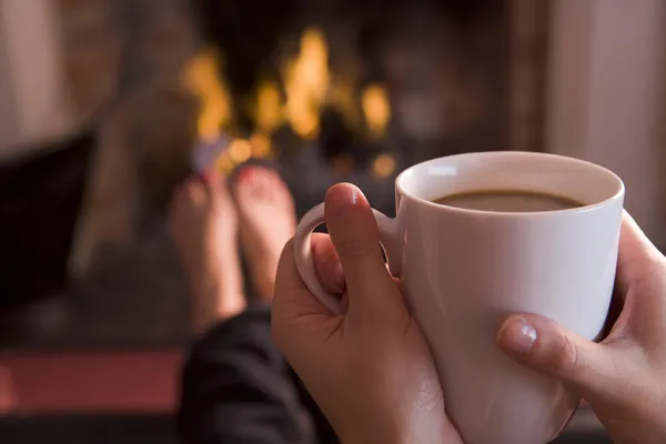 Ноги, потепление в камин с руками, проведение кофе — стоковое фото