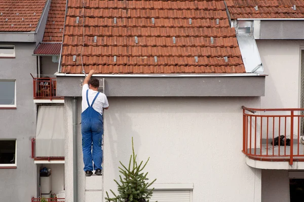 Мужчина на лестнице, забравшись на крышу — стоковое фото