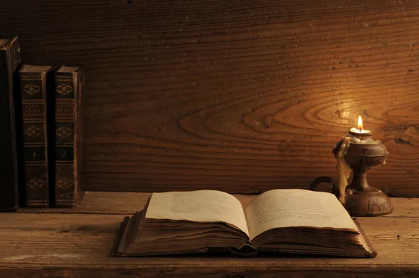 Старая книга на деревянном столе при свечах — стоковое фото